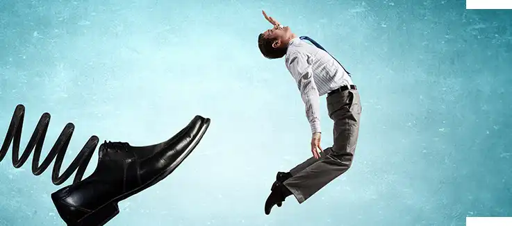 man getting kicked by a huge shoe on a spring